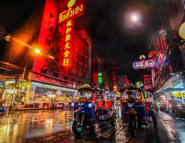 Rue animée de nuit, marché et tuk-tuks locaux